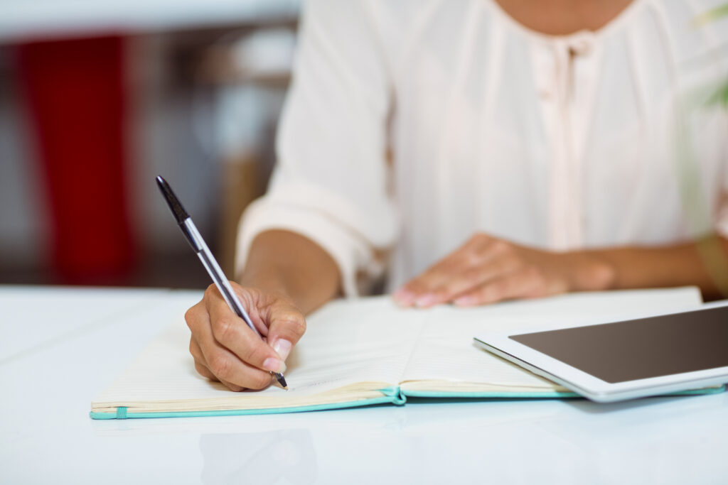 mid section of business executive writing on diary in office
